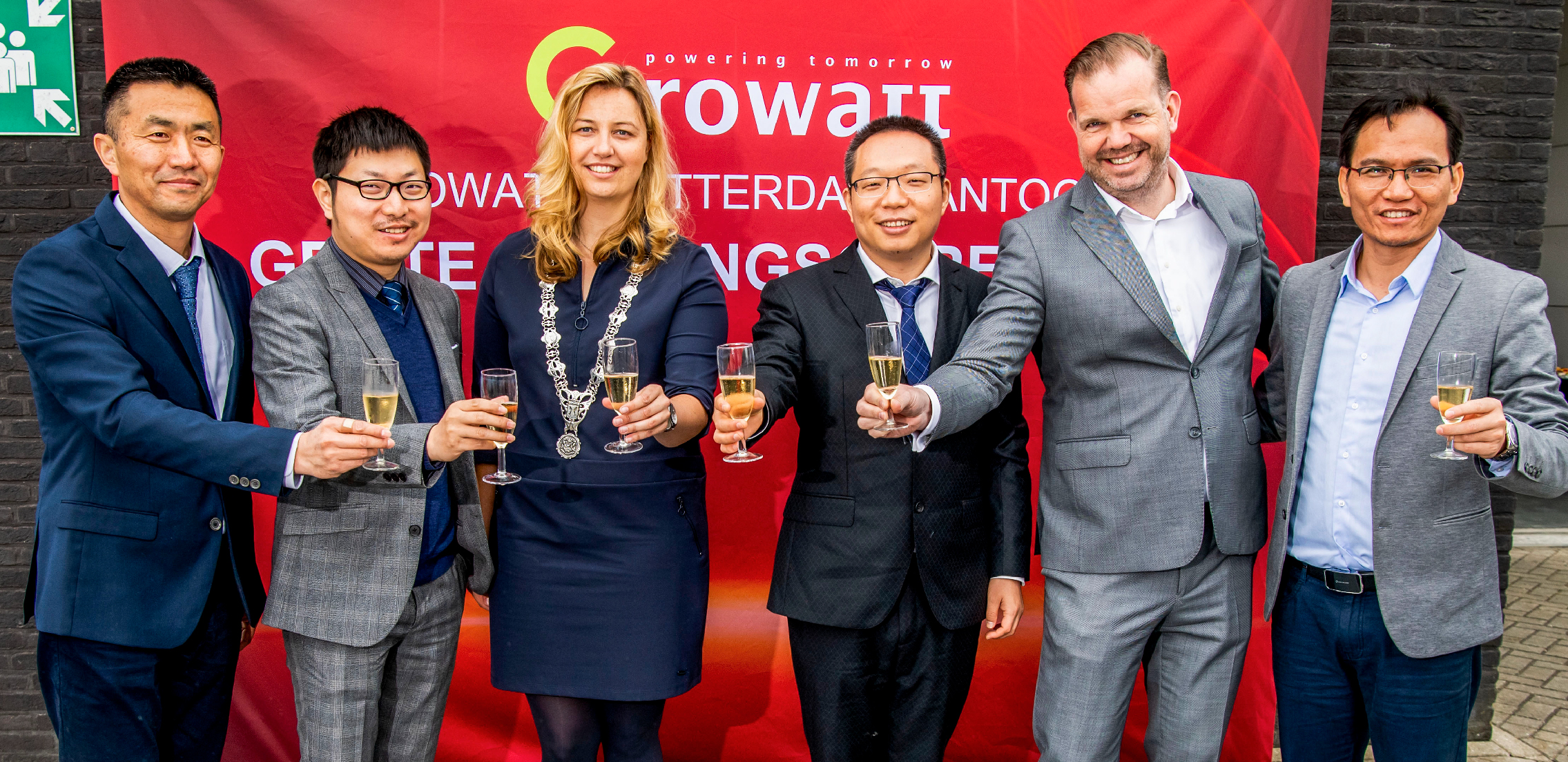 David Ding, Growatt Netherlands office, Ramon Li, Growatt’s European director, Group of formally dressed people holding champagne flutes in front of a red banner.
